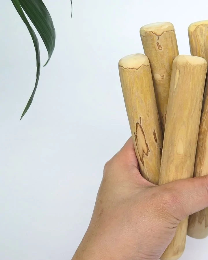A bundle of finished coffee wood dog chews held in one hand